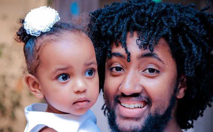 A man smiling and holding an infant.