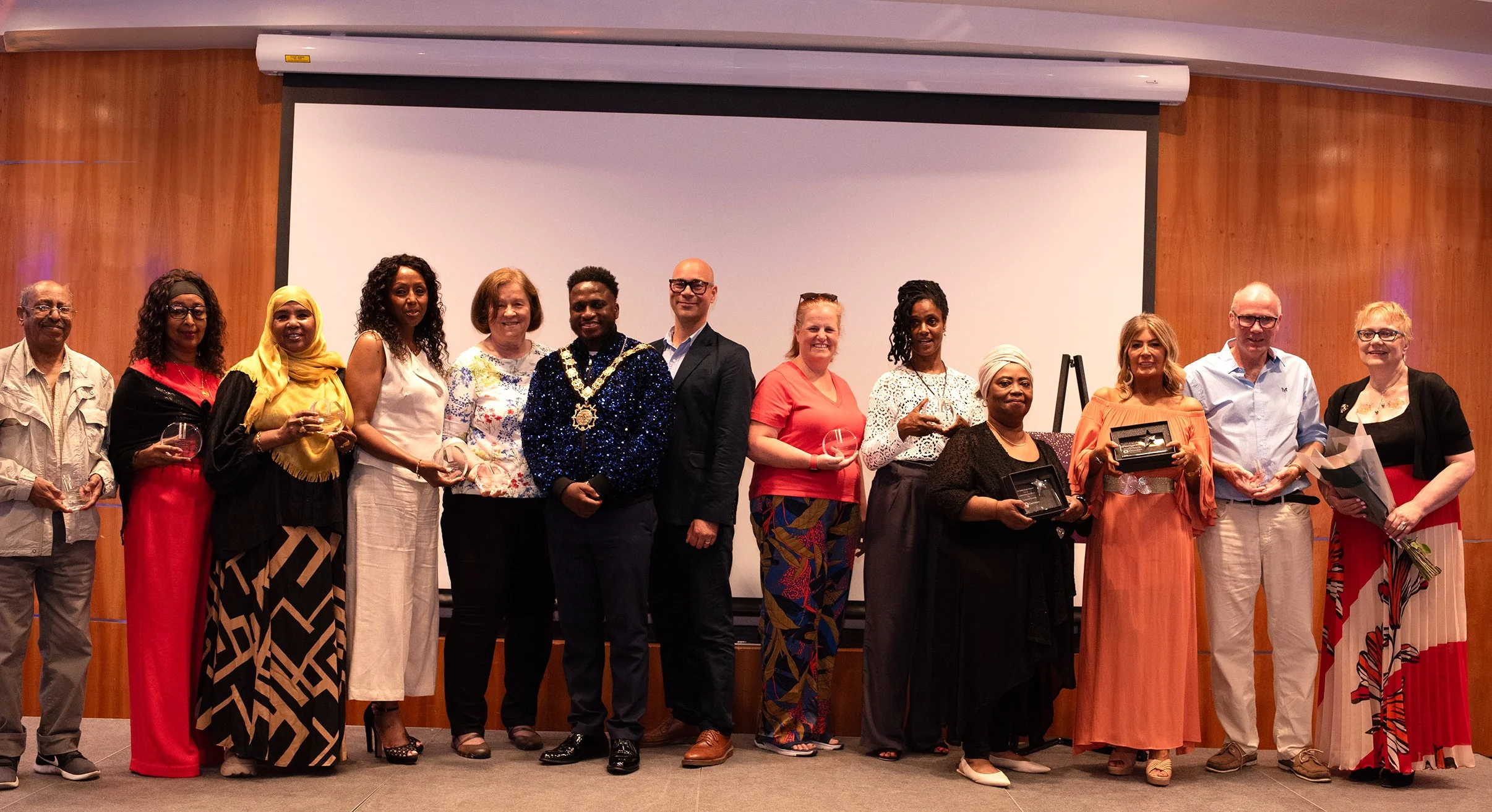 Award winning Camden foster carers (left to right) Berhan Tekle, Tsega Ghebremichael, Hawa Abdirahman-Abdi, Azeb Shonibare, Eva Somogyi, Birgitta Lambrechts, Janet Lake, Muriel Yarnie, Jacqueline Munoz and Alistair Tresidder are pictured at the Camden Foster Carers Awards with the Mayor of Camden, Councillor Eddie Hanson (centre, left), and Executive Director of Children and Learning, Tim Aldridge (centre, right), as well as retiring staff member, Elzbieta Chandrasena (far right), the Council’s Senior Development Officer for Participation in Children and Learning. Photo credit: Raj Munisami.